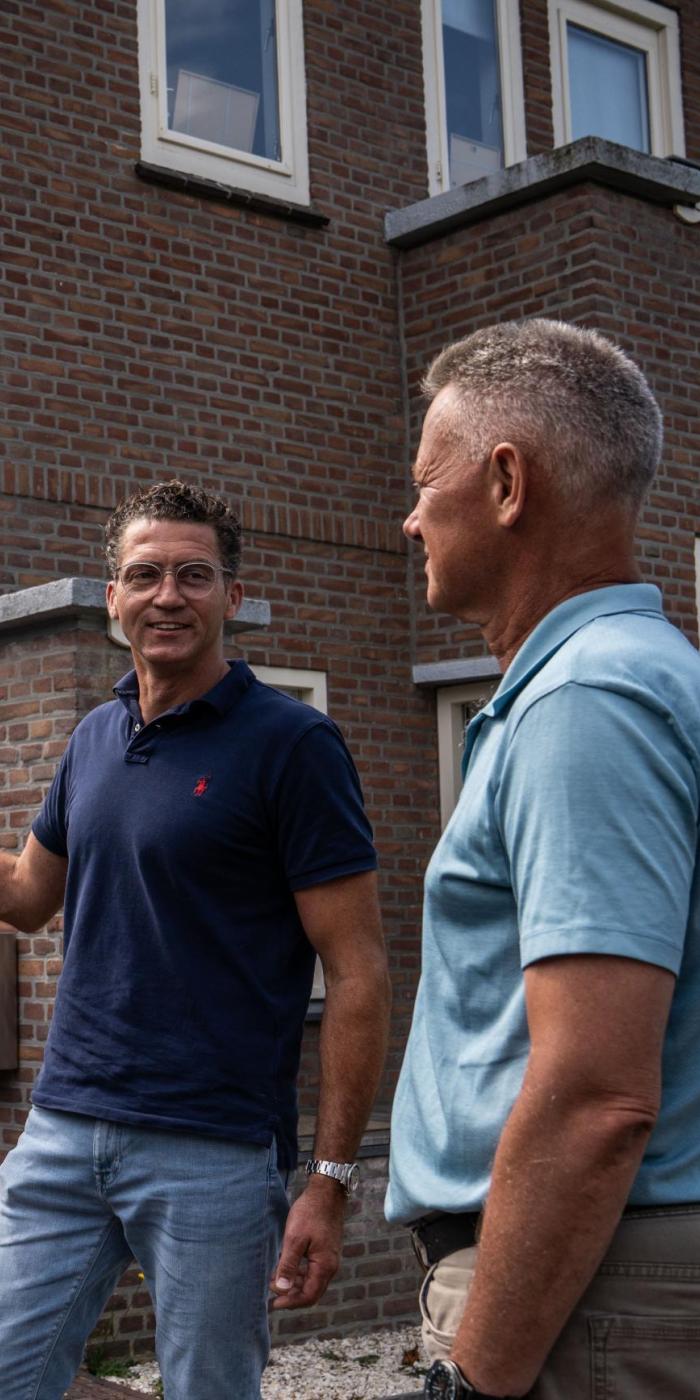 Twee personen naast huis